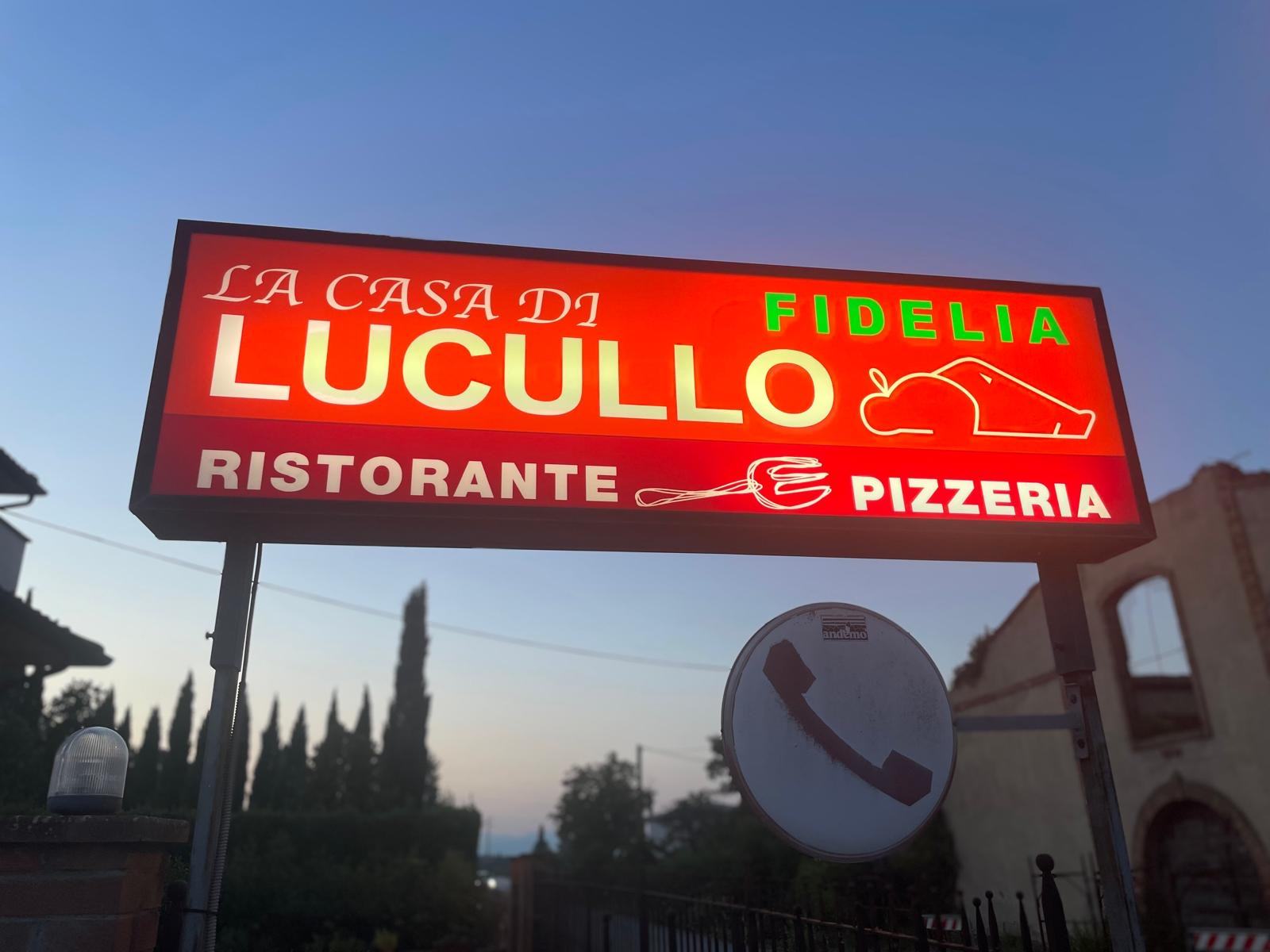 Leuchtreklame des Restaurants Lucullo in La Serra bei Sonnenuntergang.
